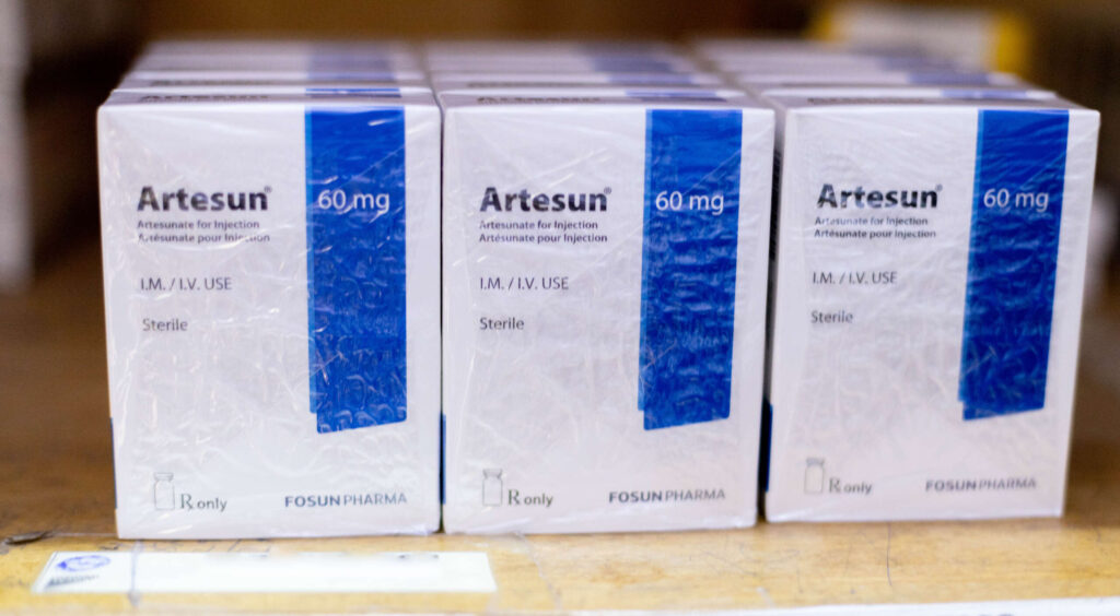 Boxes of malaria medicine sit on a shelf.