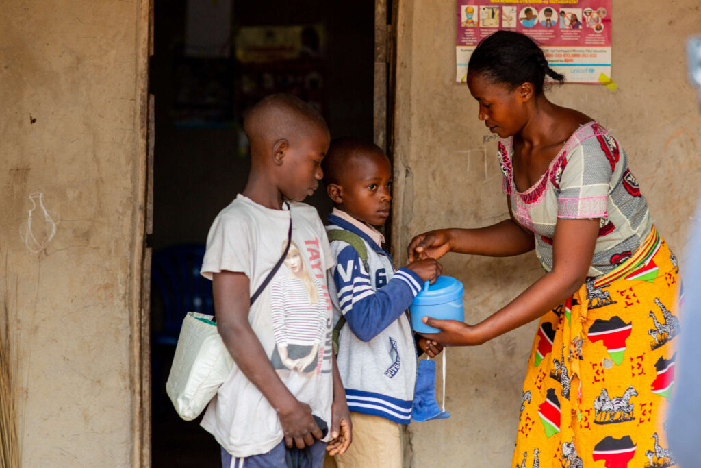 Florance hands a lunch pail to Thiery in front of their home.