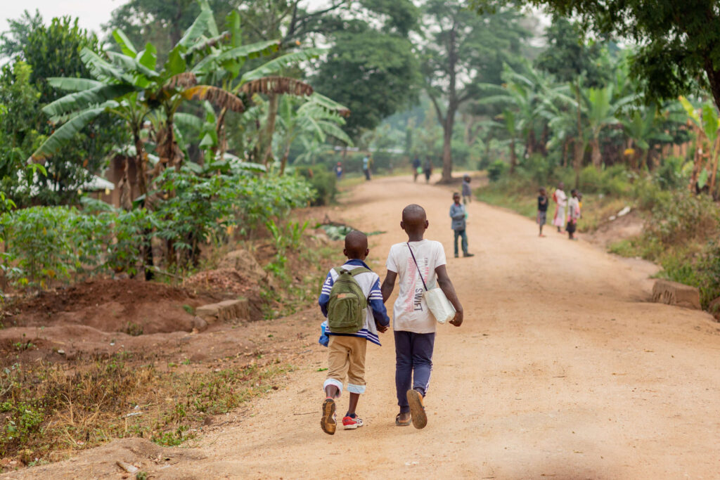 Thiery and Justine walk down a palm-tree-lined path holding hands.