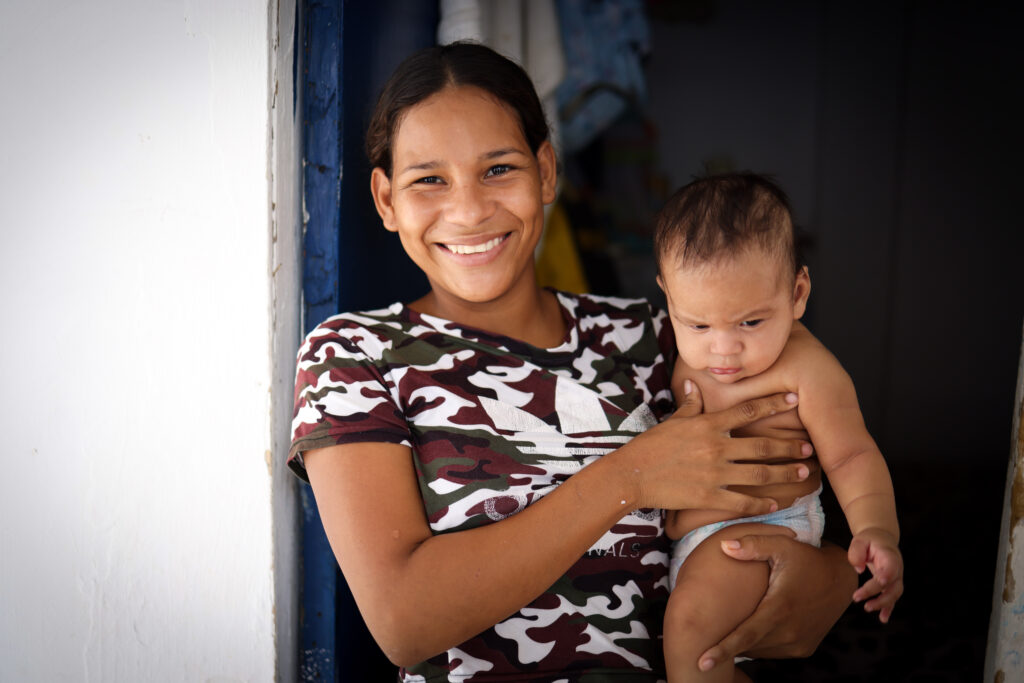Norbelis holds her baby Jorfran in the doorway in Colombia.