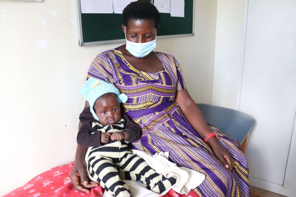 a mother and child wait in a health center to be treated for malaria