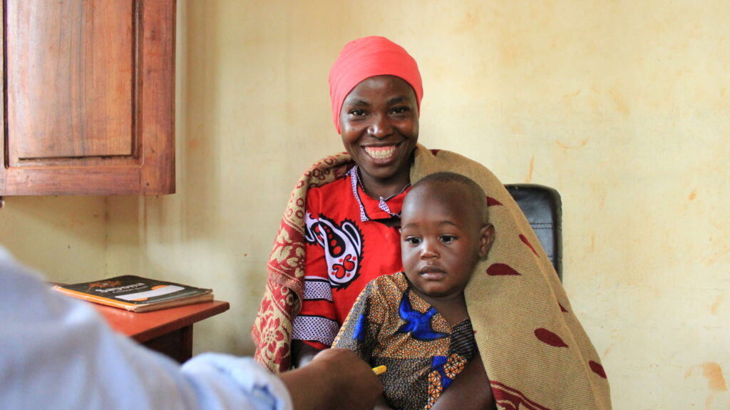 A Burundian mother who struggled with her mental health holds her baby son in a doctor's office.