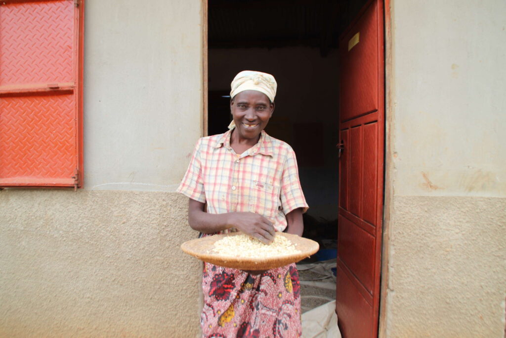 a woman poses with a basket of maize outside a classroom