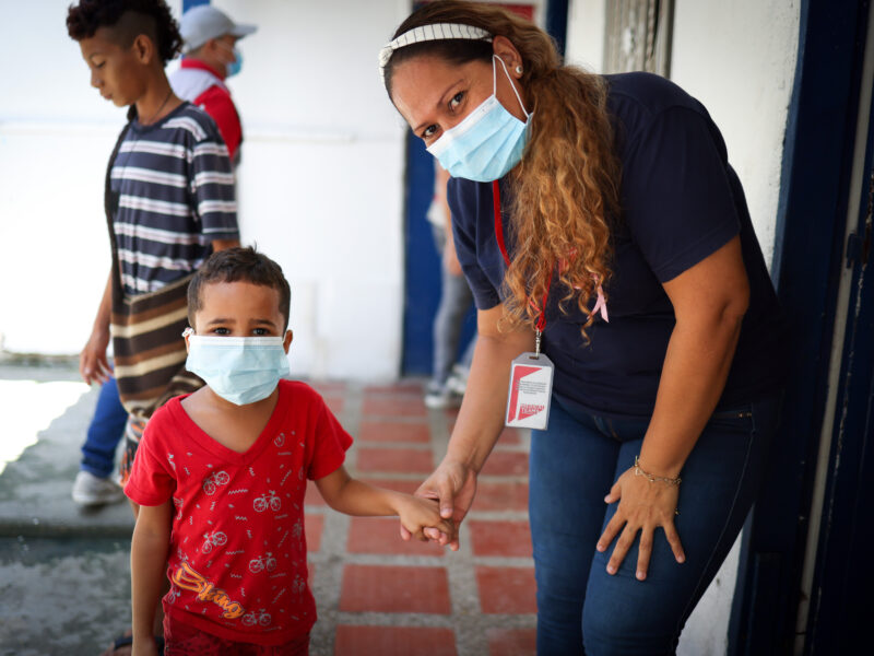 A woman hold the hand of a young child