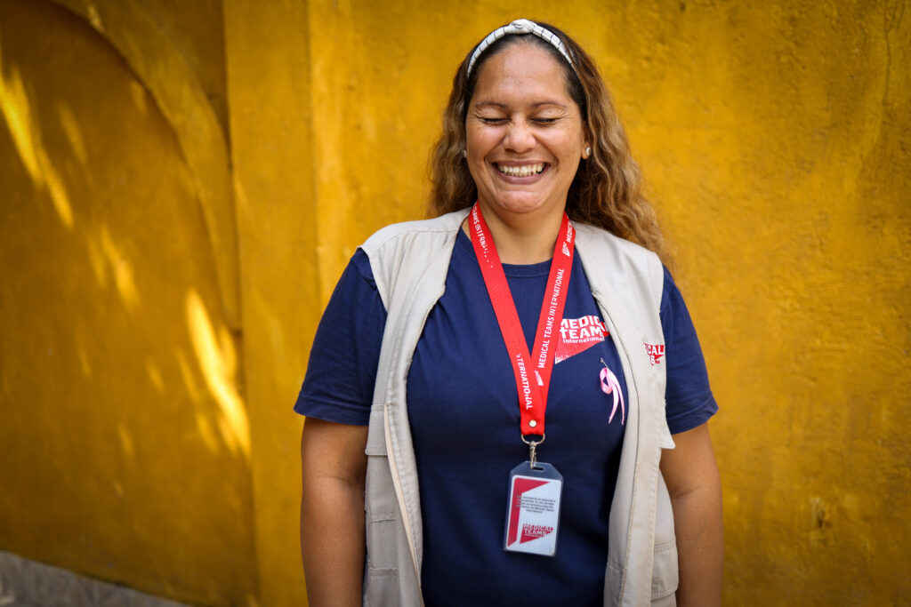 A woman laughing in front of a yellow background who inspired Marysabel Cardozo