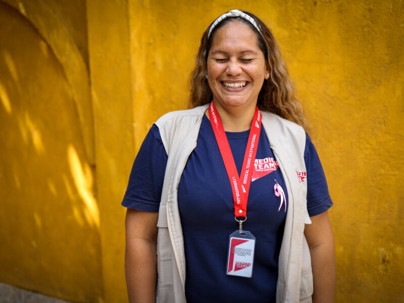 A woman laughing in front of a yellow background