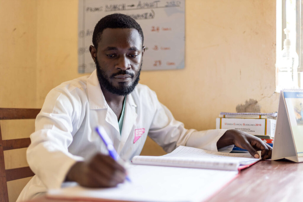Dr. Salim, a Ugandan psychiatrist, takes notes in his binder about patients.