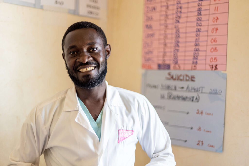 A mental health professional poses in his clinic with a wide smile.