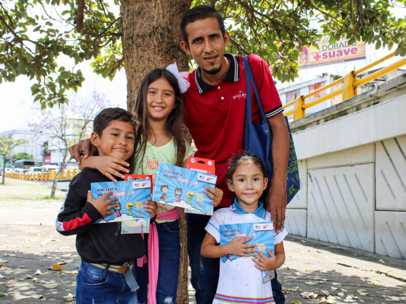 A father poses with his three children who hold up coloring books