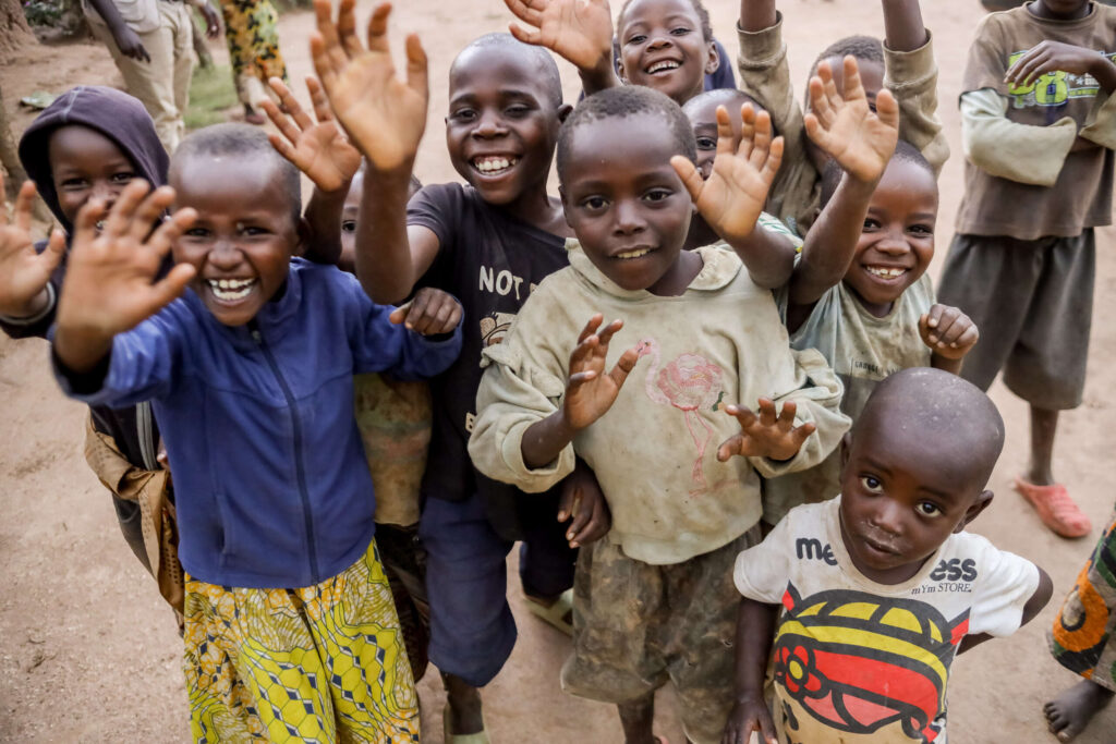 Children in Uganda smile and wave at the camera.