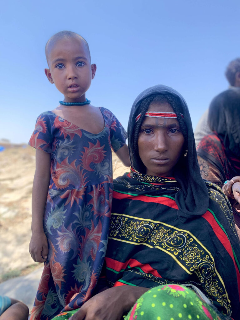 A woman and her child pose for the camera outside.