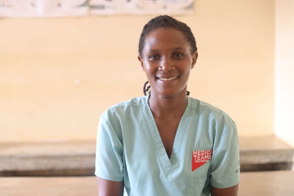 A Medical Teams nurse in Uganda smiles at the camera.