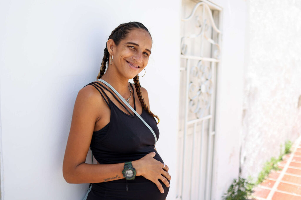 A pregnant woman smiles outside a clinic