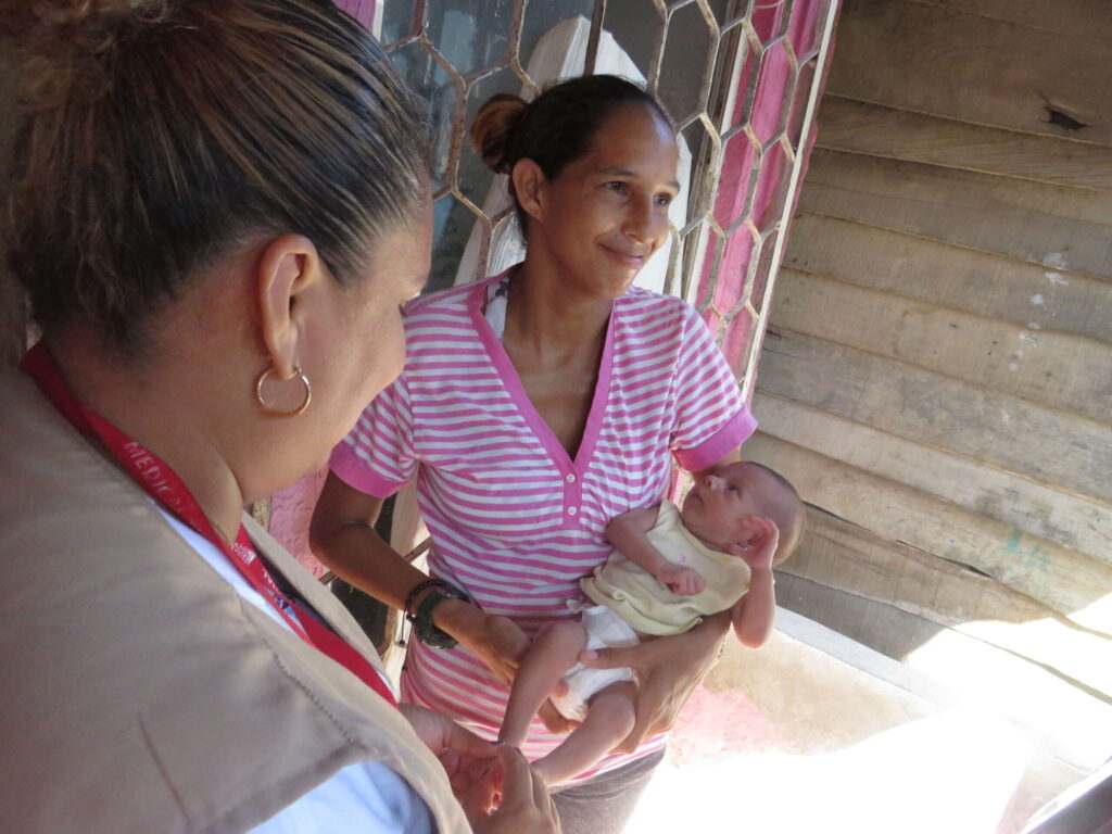 A mother smiles while holding a newborn