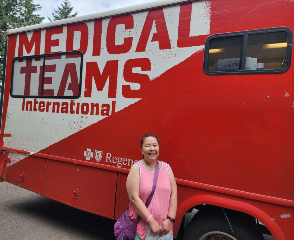 a woman stands in front of a mobile dental van