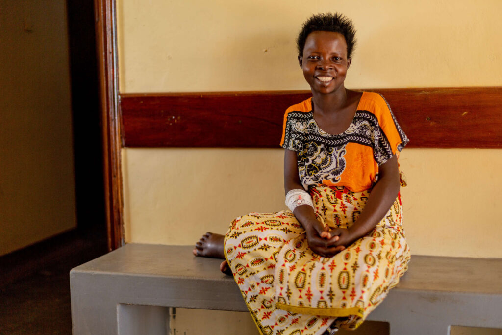 A woman on a low bench smiles at the camera