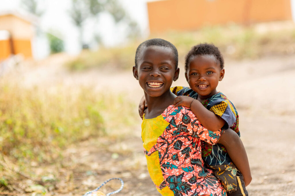 Two siblings play outside of Uganda