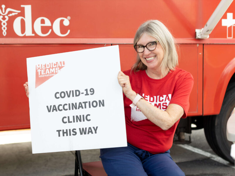 Volunteer Kathi Karnosh with the clinic sign, 2021