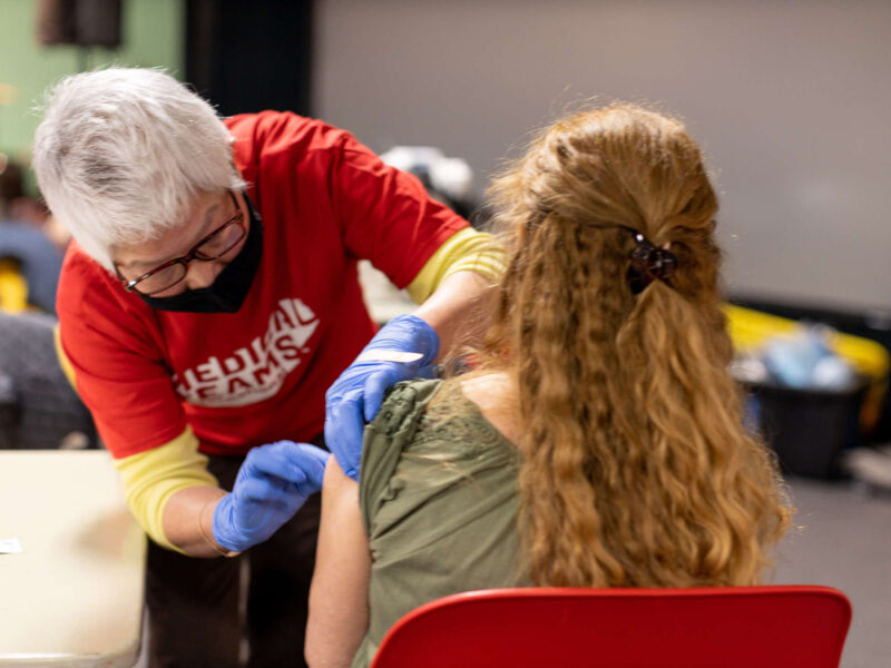Volunteer nurse places band-aid on patient following vaccination, 2021