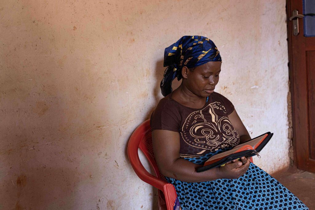 a woman reads the bible in tanzania to come and see how god wins