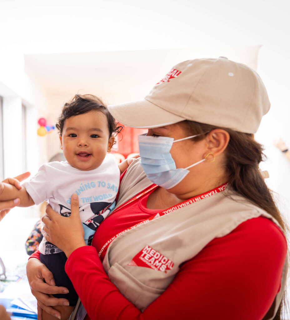 Colombia - Medical Teams volunteer holding a small smiling child at a COVID and SGBV information training