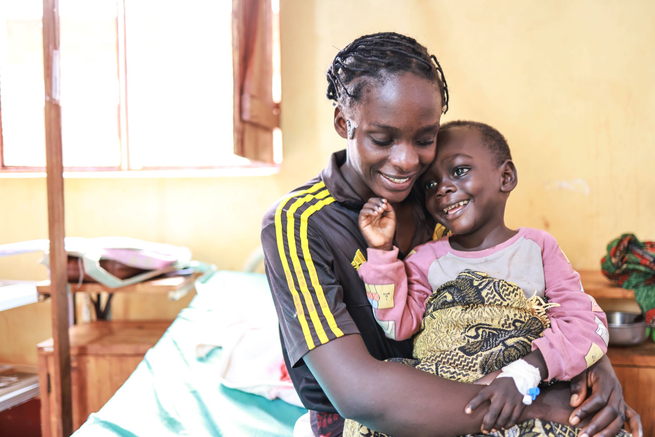 Nibizi holds her son smiling in the clinic