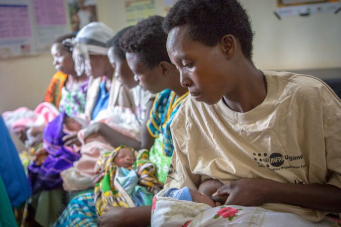 Mothers hold their babies sitting inside a Medical Teams clinic in Uganda