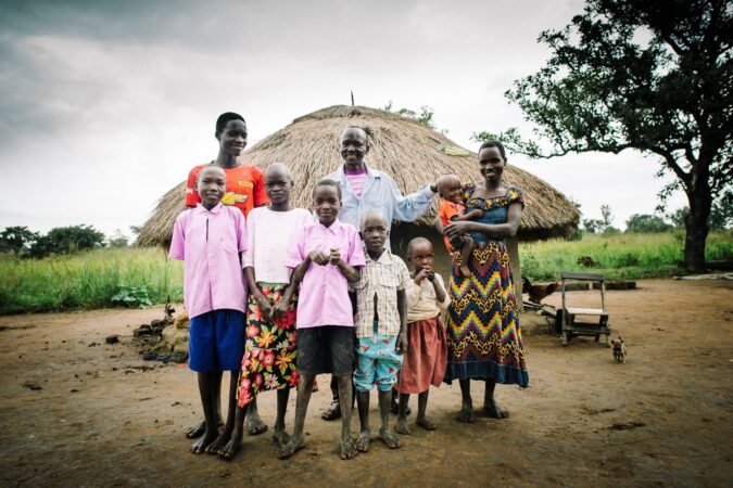 A family stands outside in a refugee settlement in Uganda