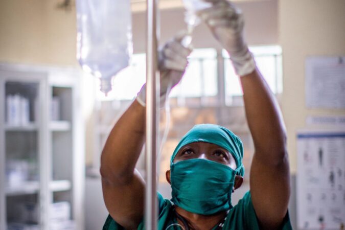 A Medical Teams nurse hangs an IV fluids bag in the clinic