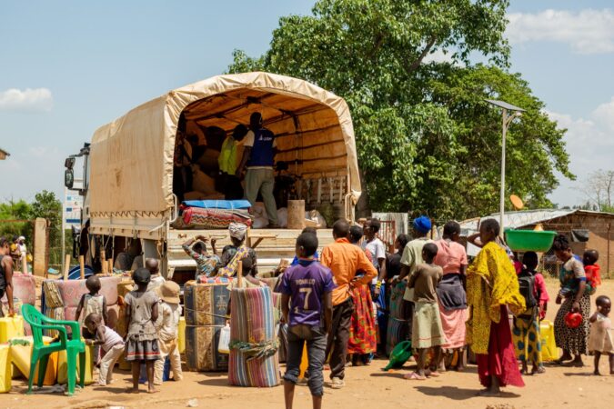 Refugees at the welcome center in Uganda load onto a transport truck taking them to a settlement