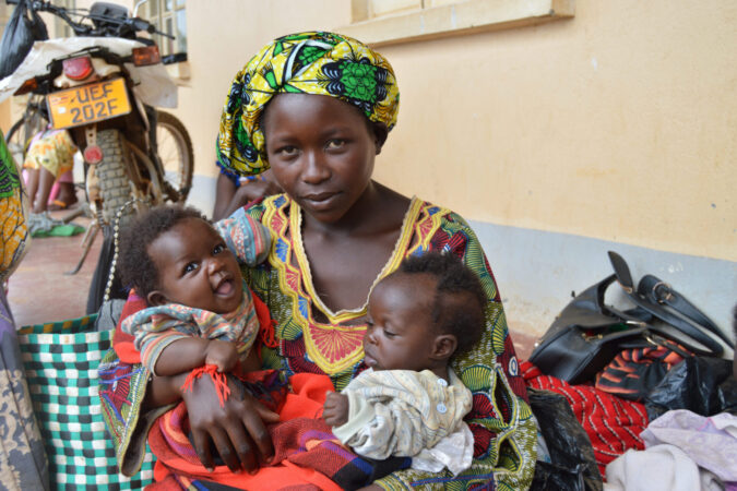 A mother holds her two babies in Uganda, 2015