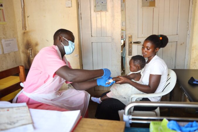 Paska holds her daughter Keisi while a Medical Teams health worker gives her medication to heal her malaria