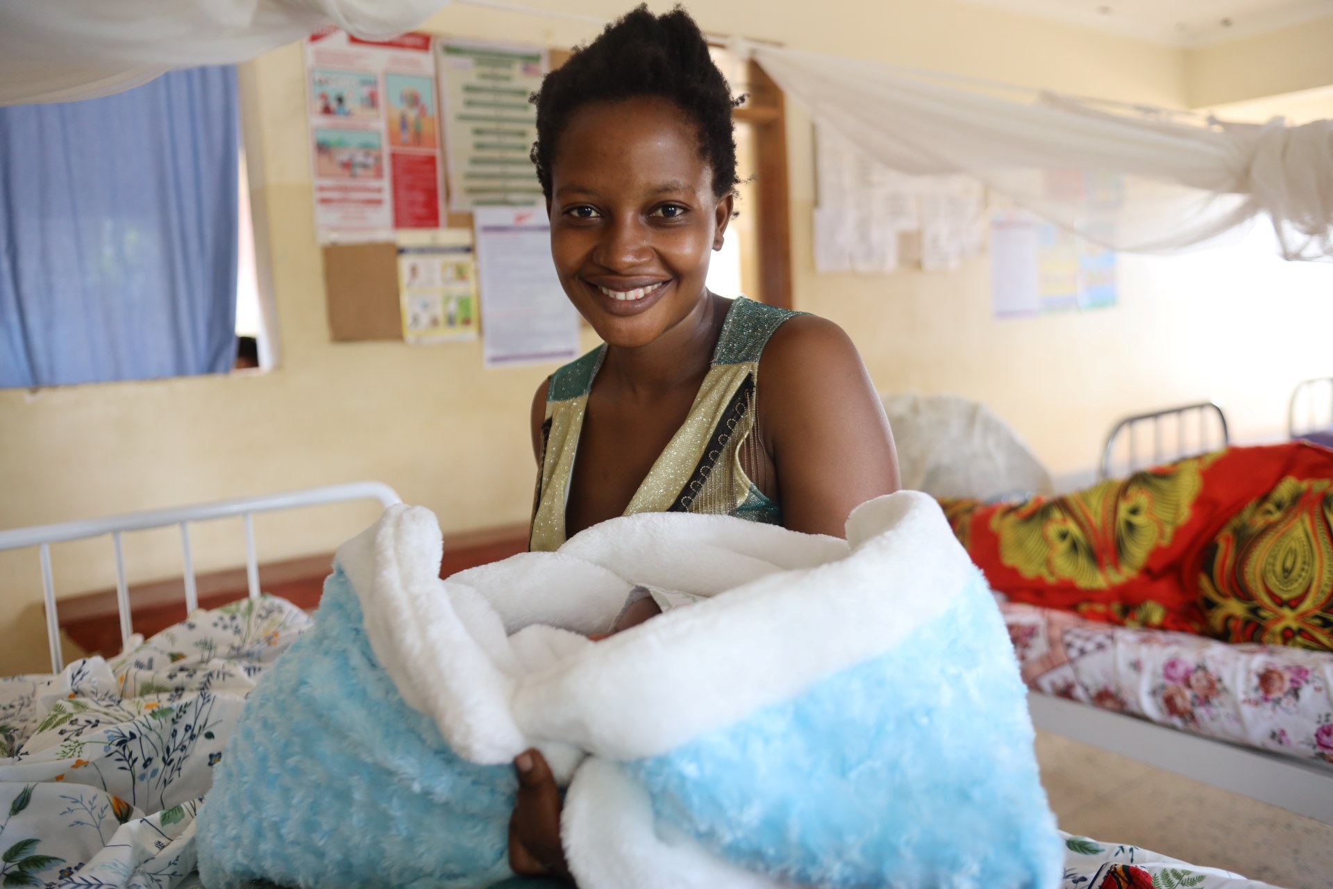 Devota holds her baby, Ezekiel in a health clinic in Uganda