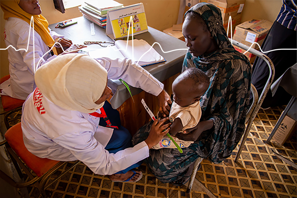 A nutrition assistant in Sudan cares for a child named Ramadan while he sits on his mother's lap.