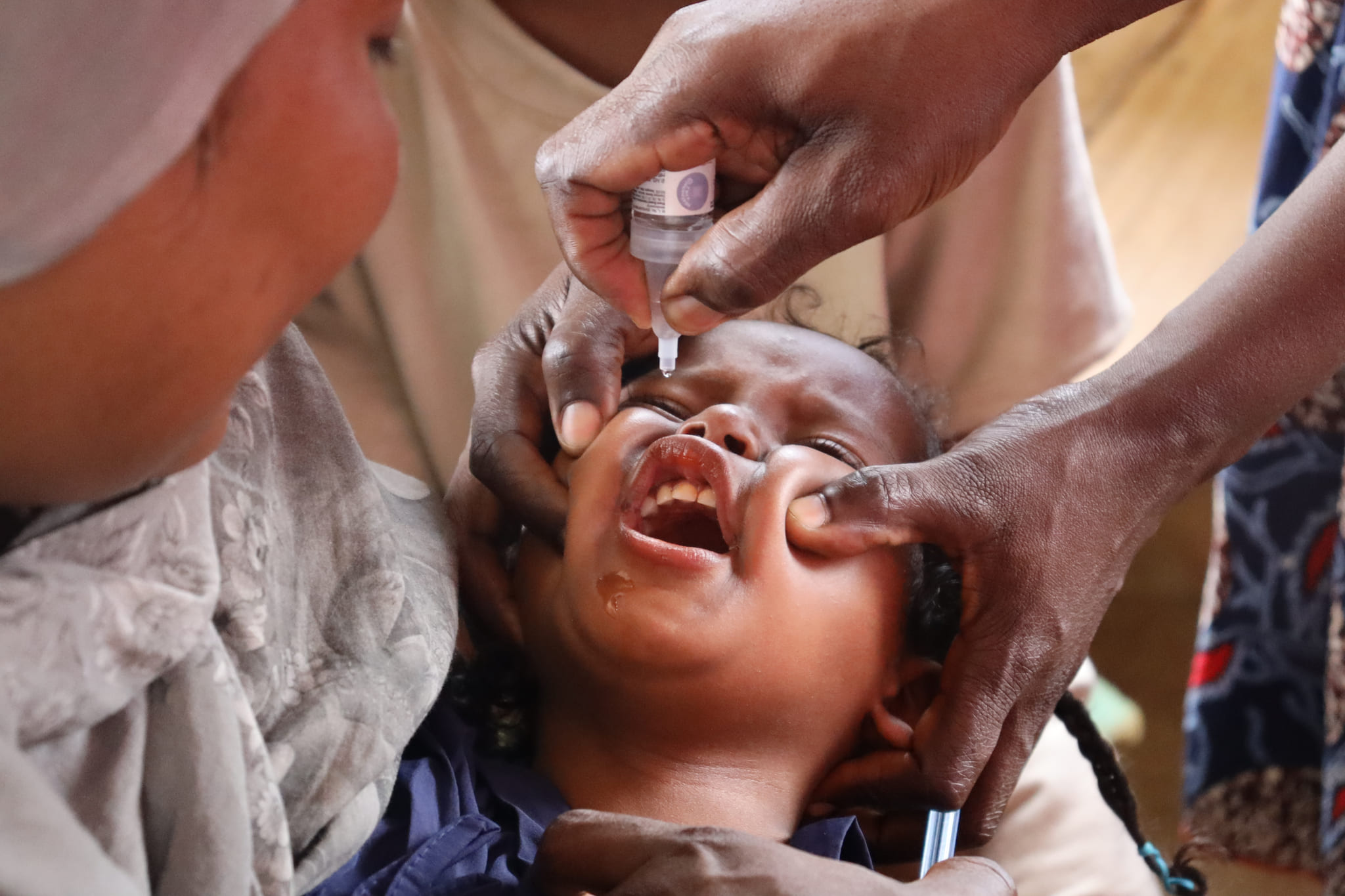an oral polio vaccine is administers by Medical Teams staff to a child in Uganda