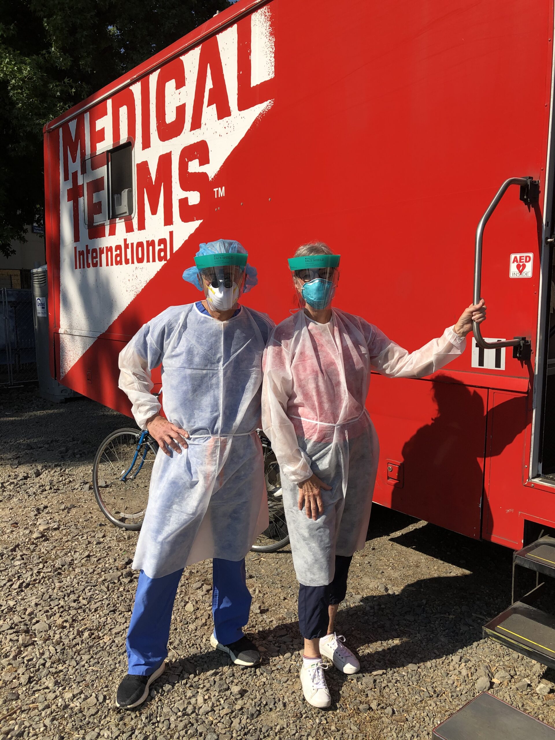 Dr. Kurt and Kathi Karnosh stand outside a mobile clinic in dental gear