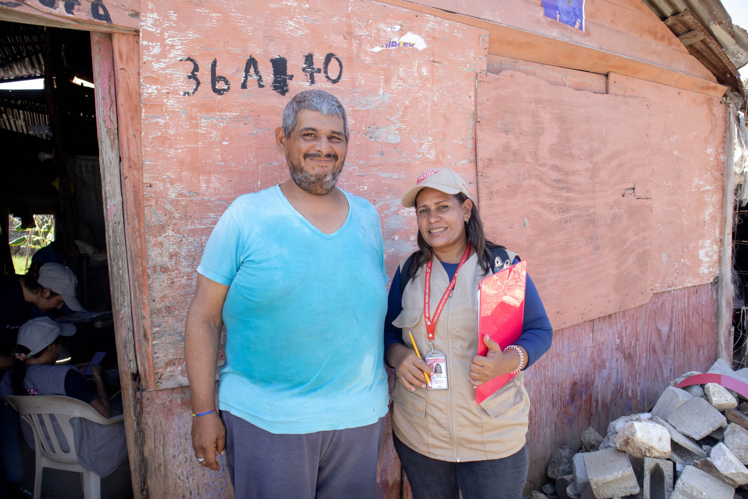 Luis standing outside his home with volunteer Tania.