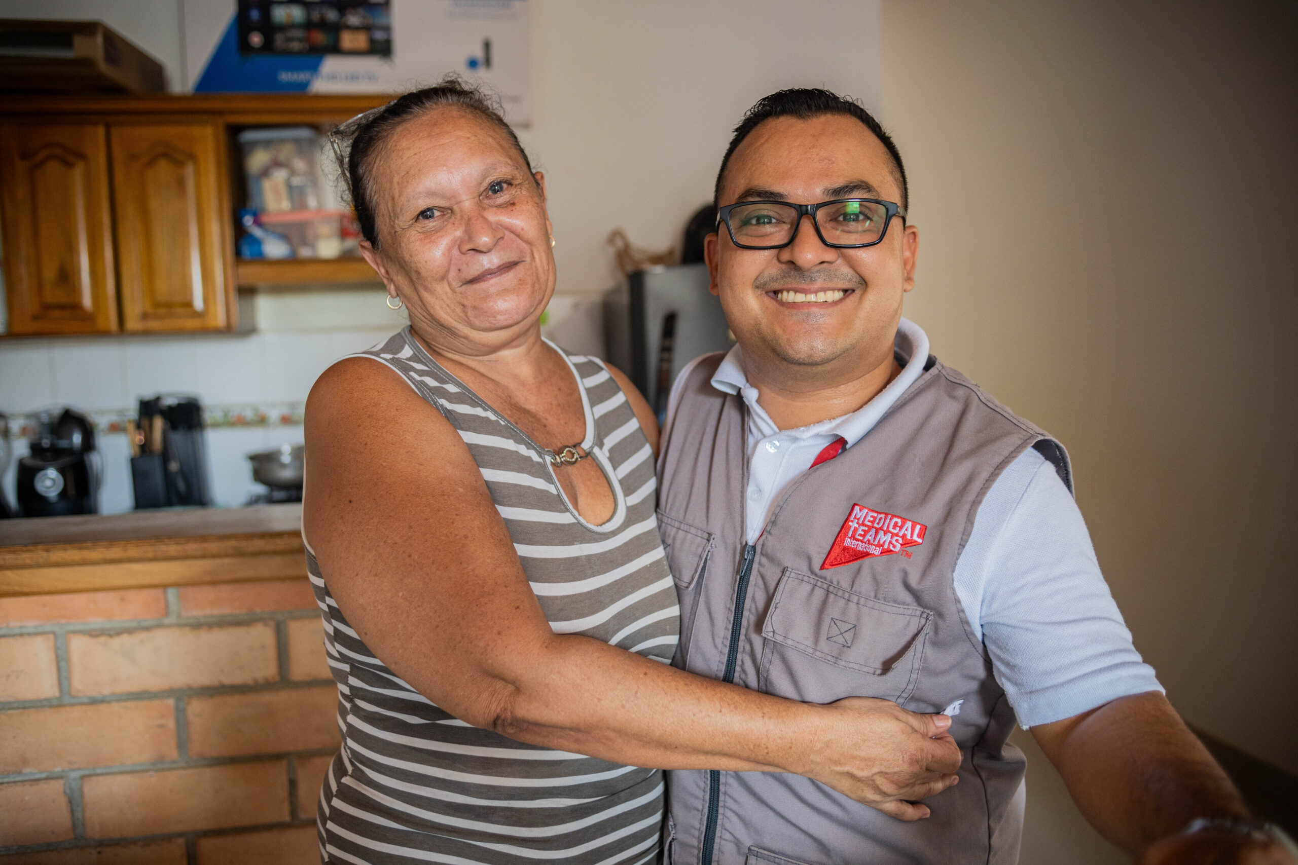 Venezuelan migrant Morelba Franco embraces Martin, a Medical Teams staff member, in her home.