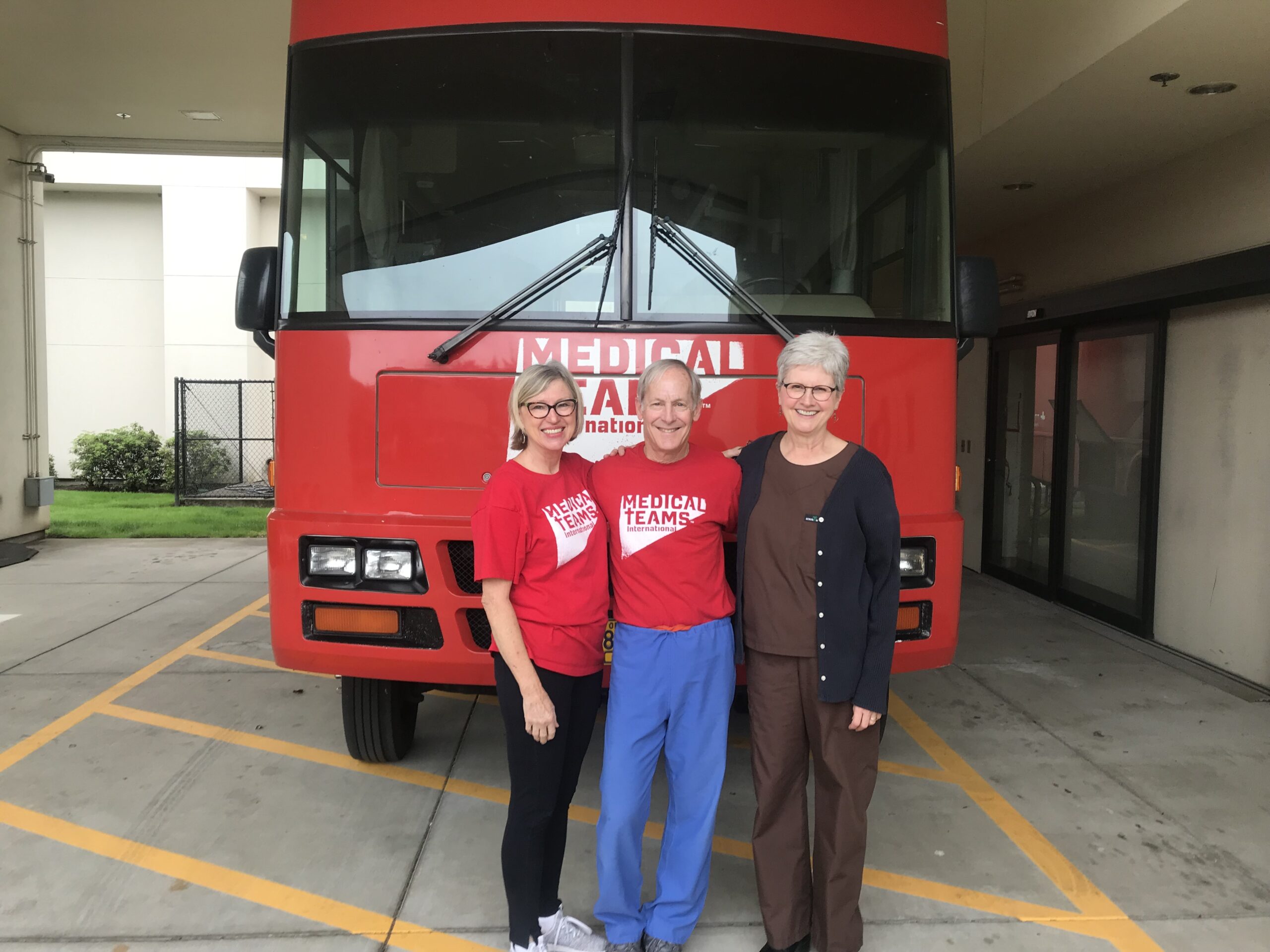 Dr. Kurt stands with two volunteers outside a Care & Connect Mobile Health Clinic in Oregon