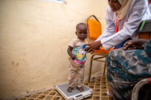 Ramadan is weighed on a scale by a Medical Teams Nutritionist