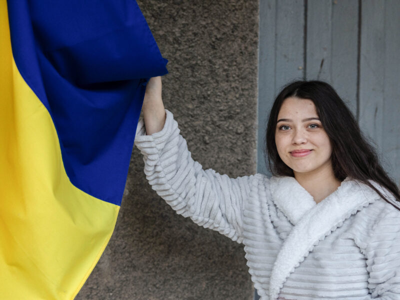 A young girl holding up the Ukranian flag.