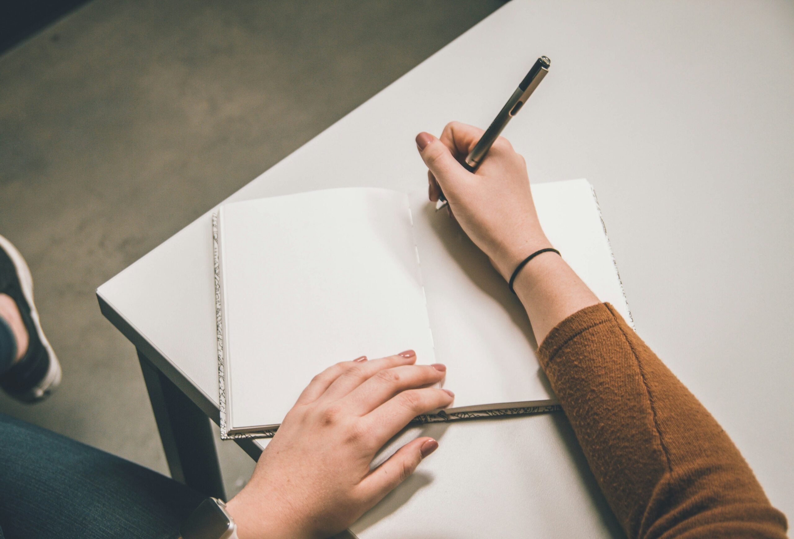 Photo by Kenny Eliason of a person writing down notes at a table