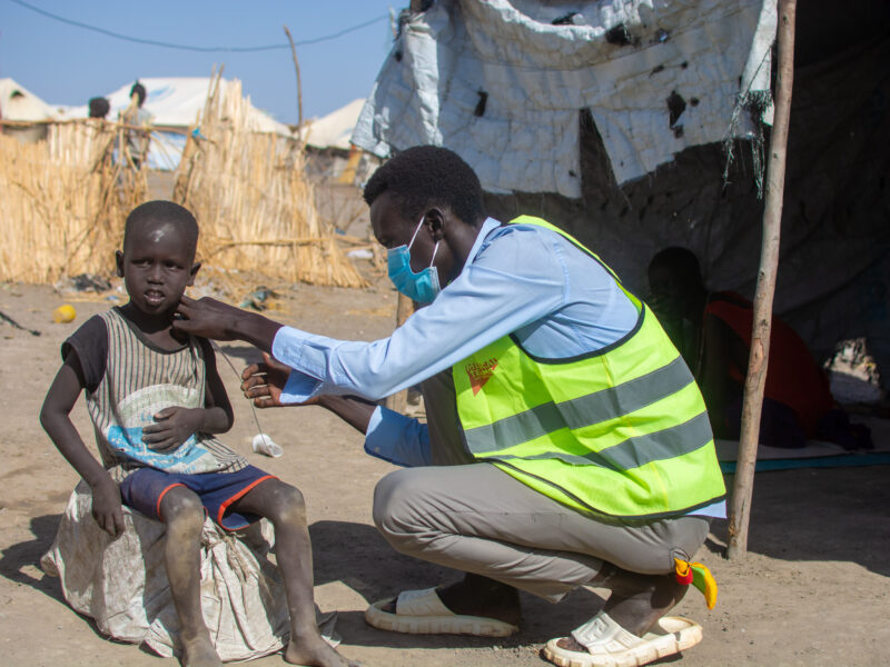 A community health volunteer screening a child for malnutrition in Sudan.