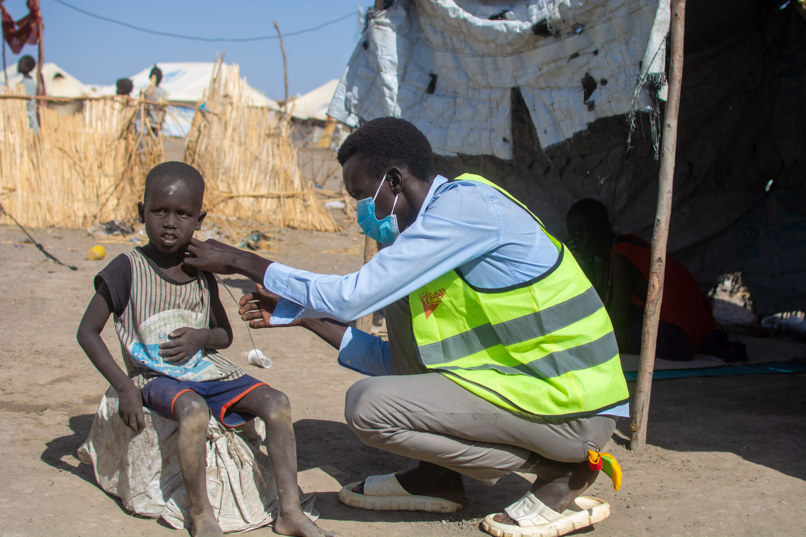 A community health volunteer screening a child for malnutrition. 