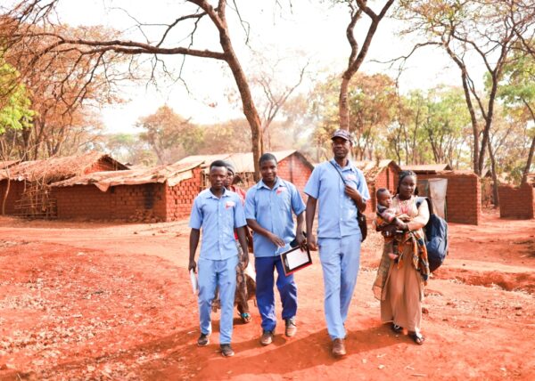 A group of community health workers walks through homes of refugees in Tanzania