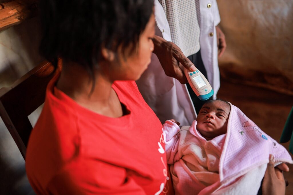 A health worker in Tanzania checks the temperature of a baby.