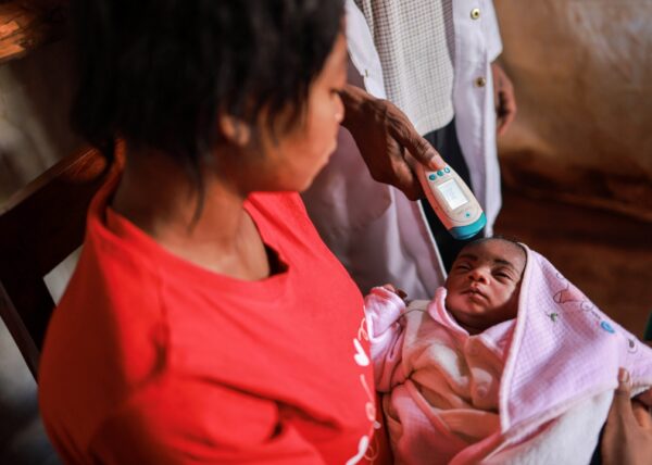 A health worker in Tanzania checks the temperature of a baby.