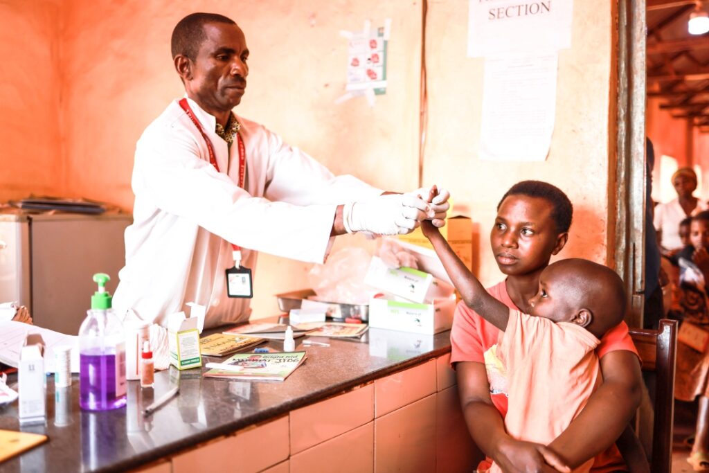 A young boy named Reuben is held by his mother during lab work in Tanzania at a Medical Teams clinic.