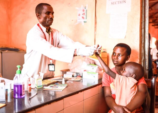 A young boy named Reuben is held by his mother during lab work in Tanzania at a Medical Teams clinic.