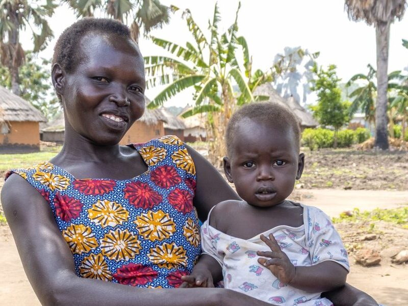 Beatrice holds her baby outside in Uganda